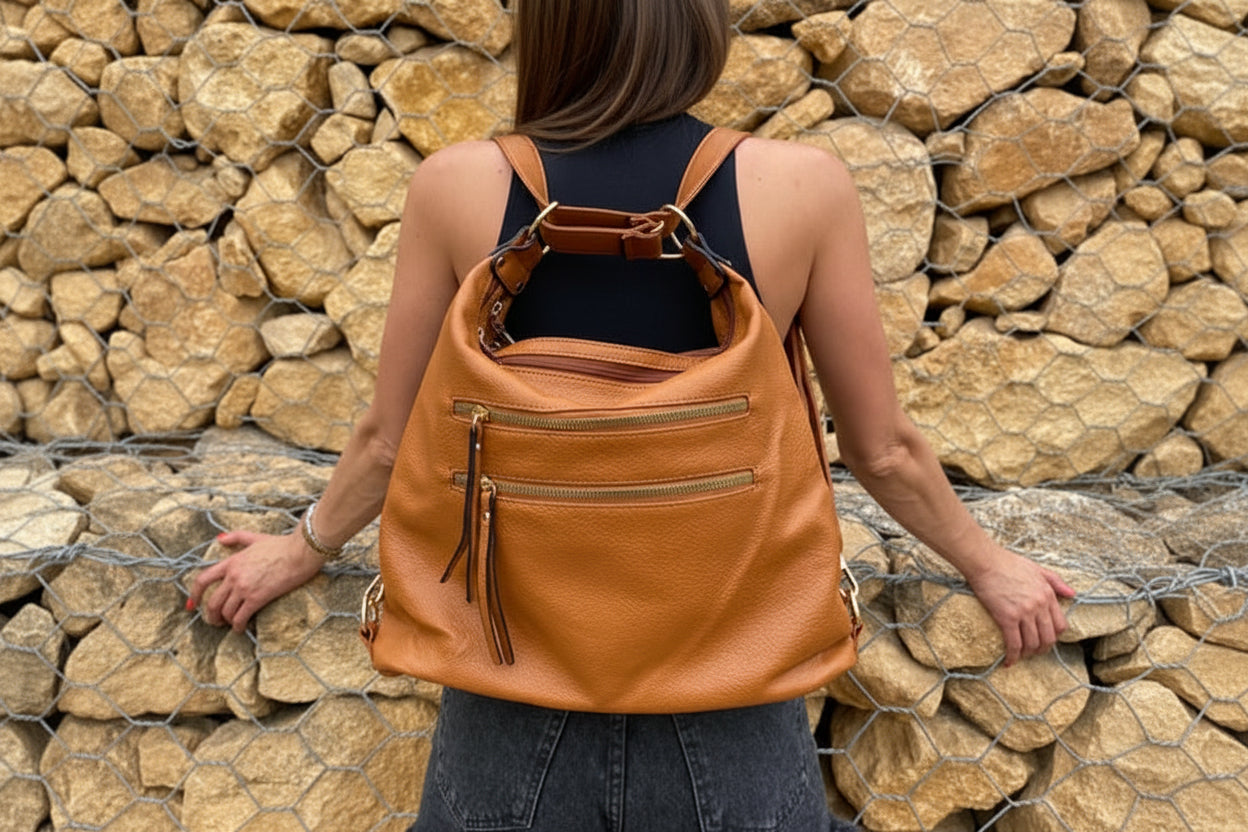 Person wearing a tan backpack against a stone wall