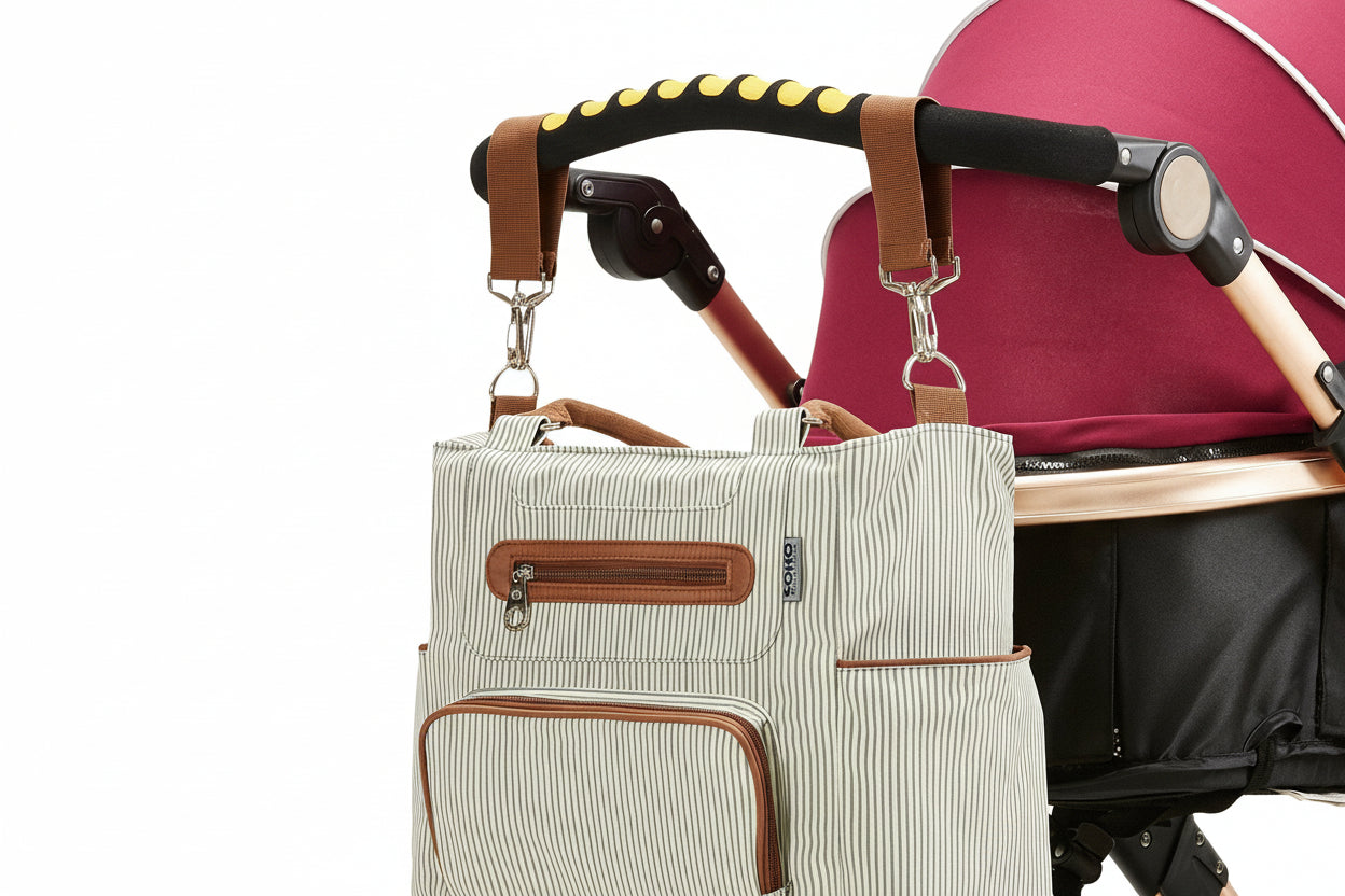 Beige striped diaper bag attached to a pink stroller on a white background