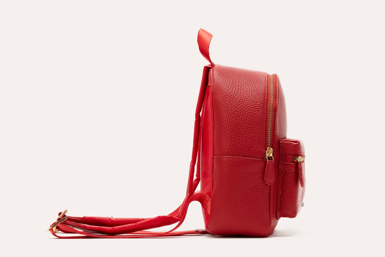 Red leather backpack with a strap on a white background