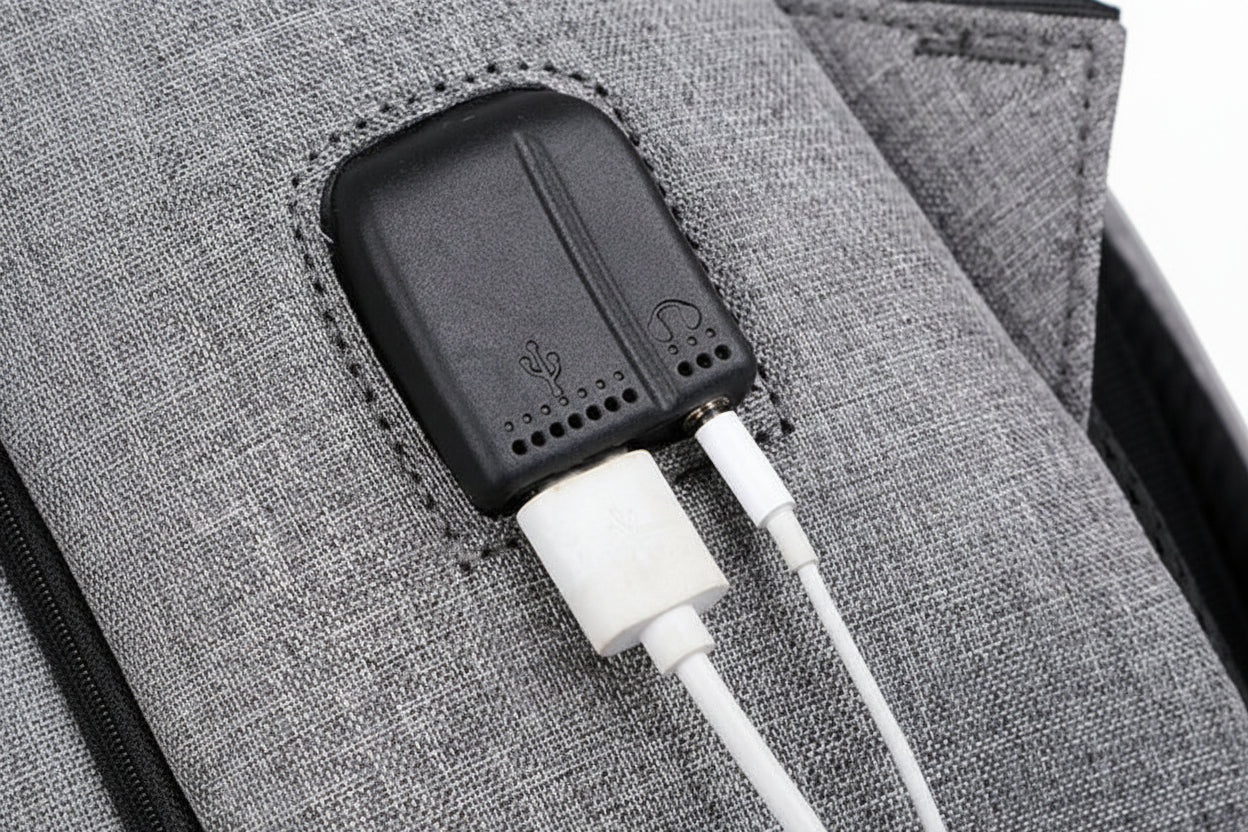 A backpack with white cable attached to a gray textured surface