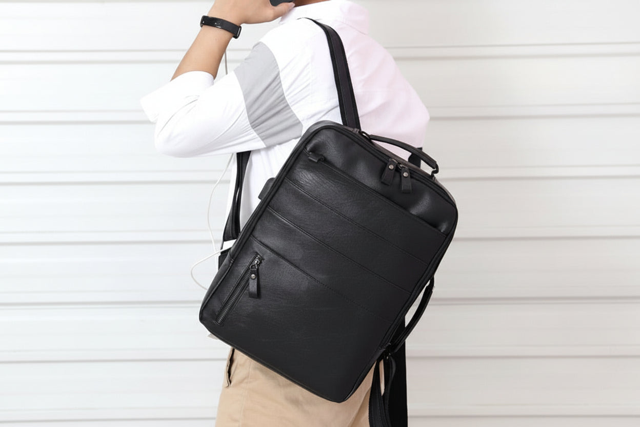 Person carrying a black backpack with a phone to their ear against a white background