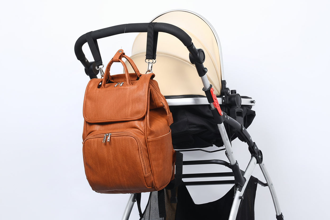 Brown leather backpack attached to a baby stroller on a white background