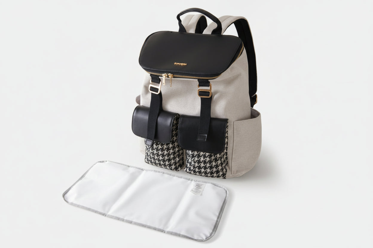 Backpack with black top section and houndstooth pattern, accompanied by a white changing pad on a light gray background.