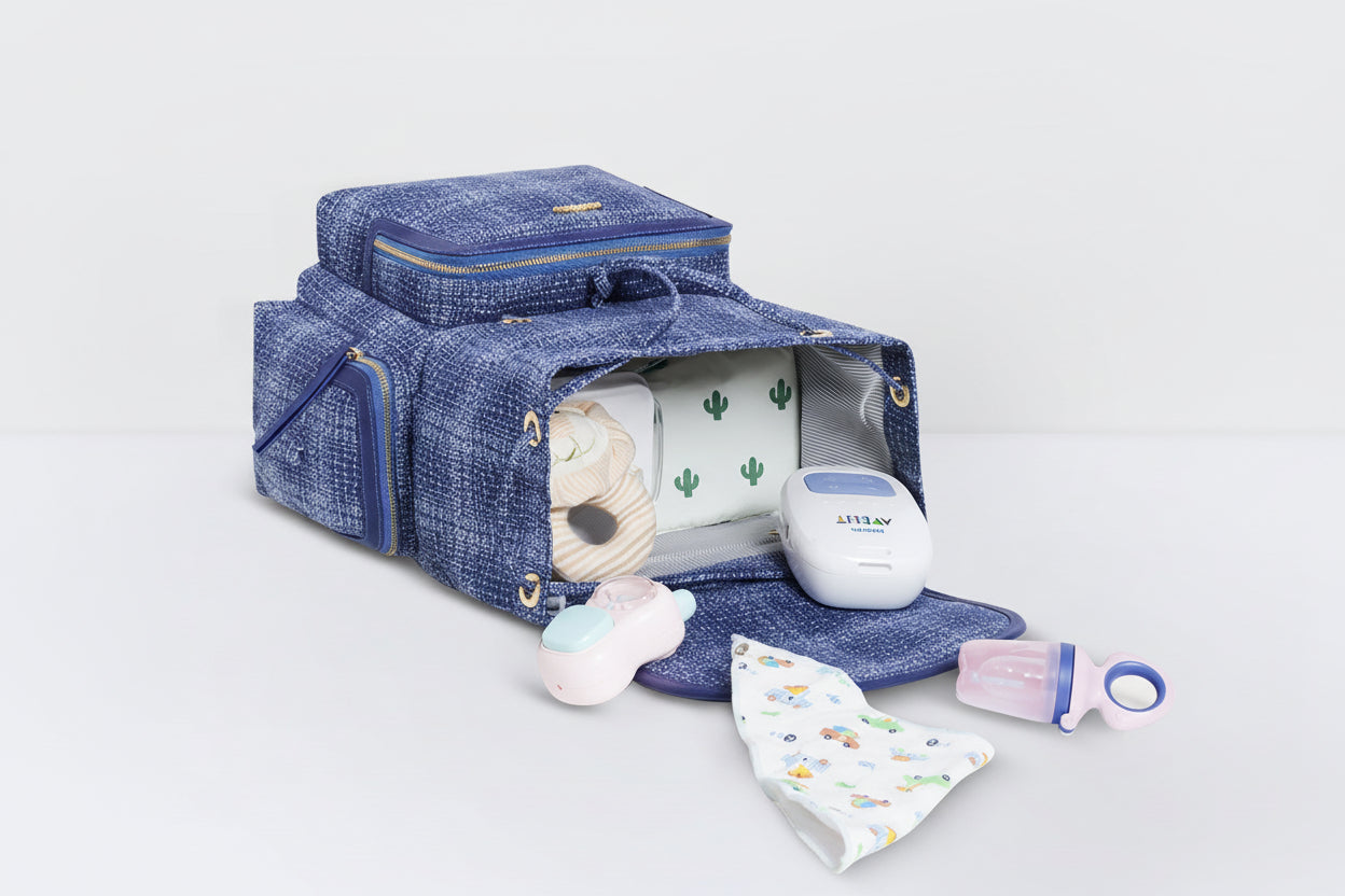 Blue baby diaper bag with baby items on a light gray background