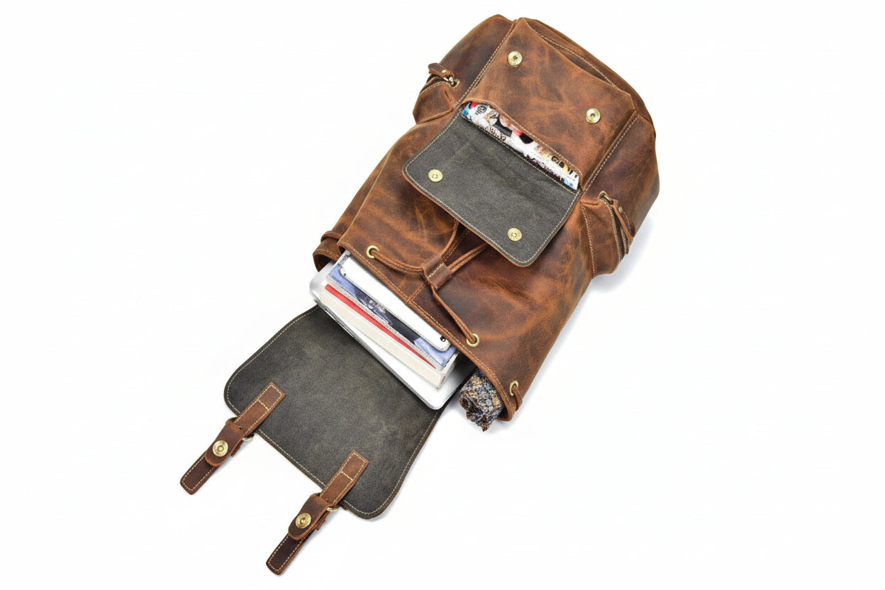 Brown leather backpack with open front pocket on a white background